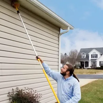 service tech sweeping exterior of home